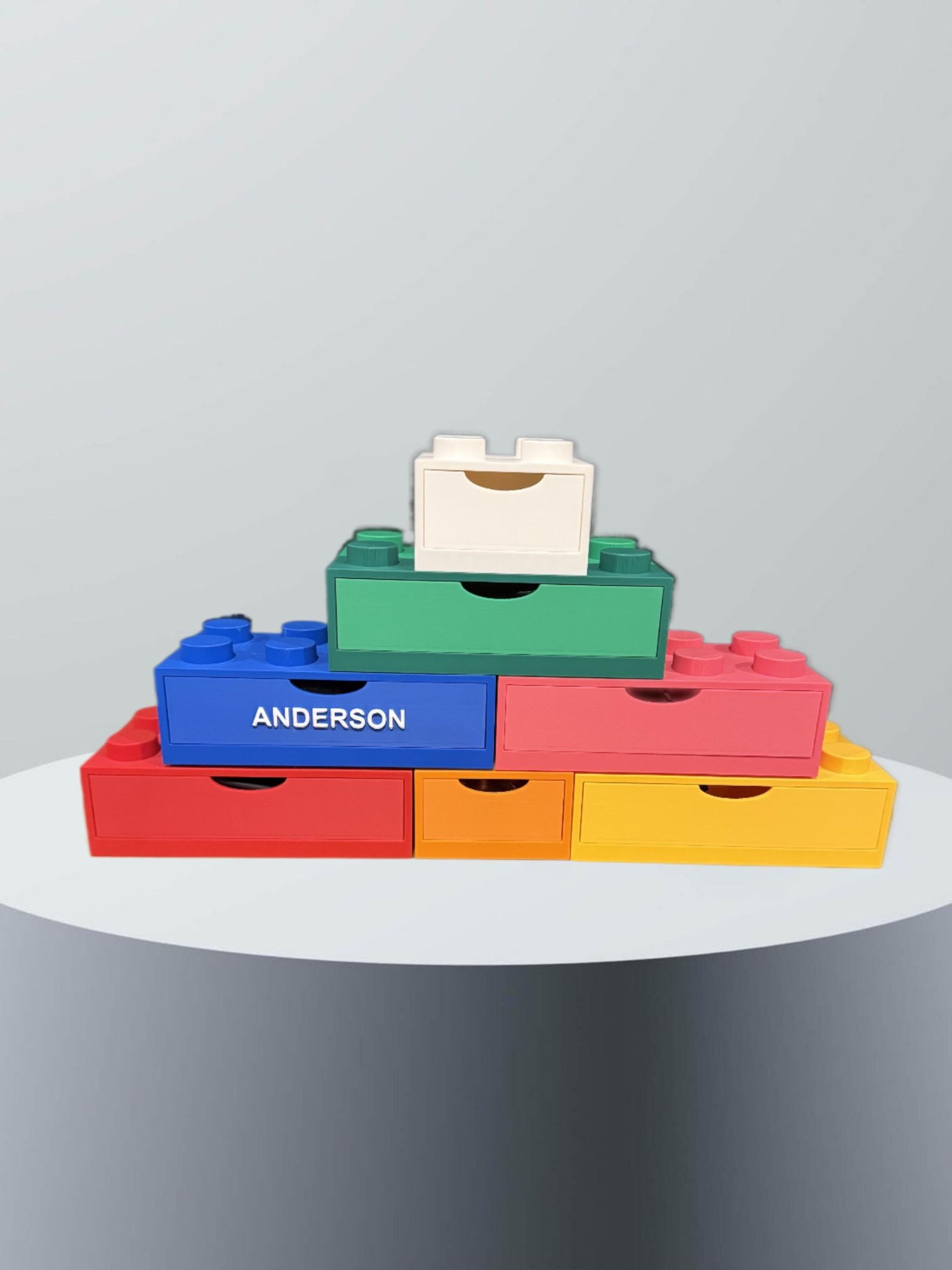 Personalized brick drawer organizer — seven stackable storage bricks in red, blue, green, pink, orange, yellow, and white with a custom name brick