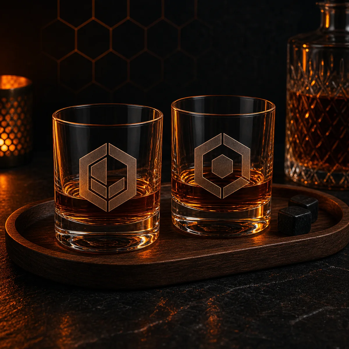 Two laser-engraved whiskey glasses with hexagon monograms on a walnut tray